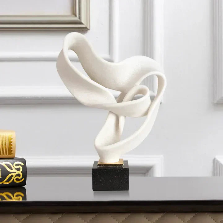 Fitlybuy Vida modern white resin sculpture with an abstract, flowing ribbon design on a black base, displayed on a desk.
