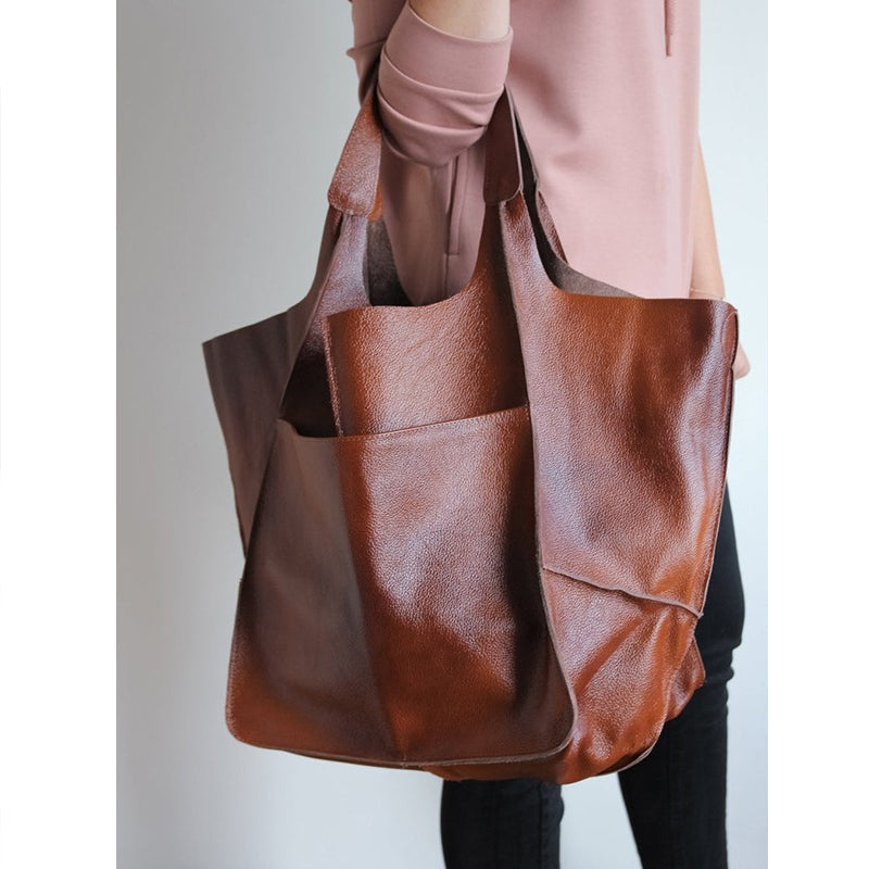 Fitlybuy oversized brown leather weekender bag with structured handles and front pocket carried over the shoulder.