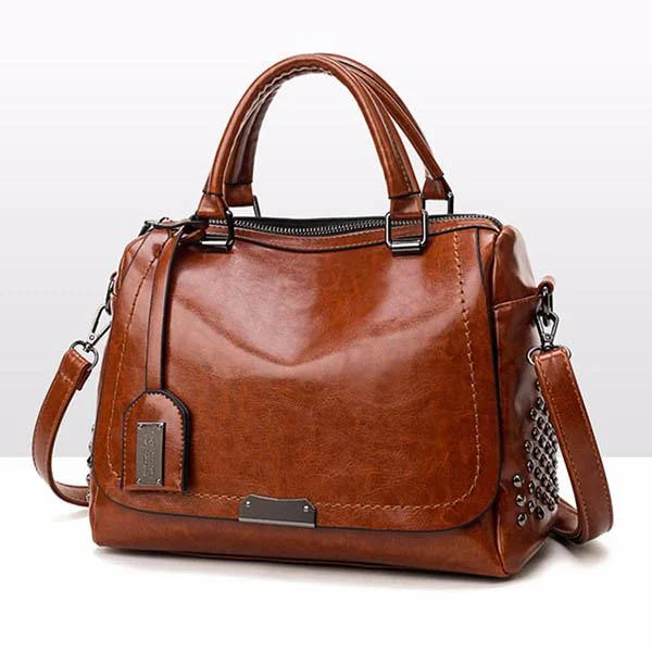 Brown soft leather shoulder bag with top handles, metal hardware, side stud details, and a detachable shoulder strap.