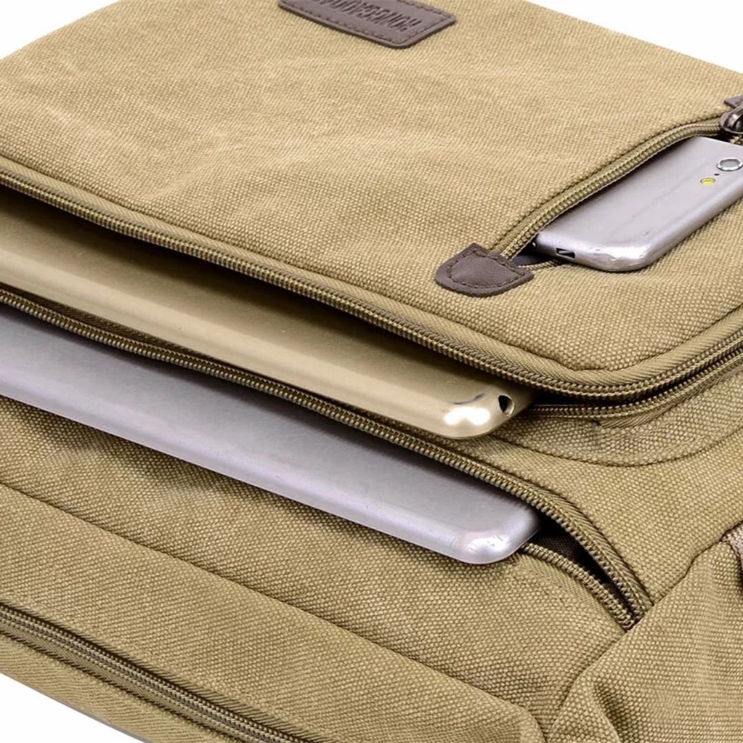 Tan canvas Fitlybuy TravelPro bag with multiple zippered pockets containing a tablet, laptop, and smartphone.
