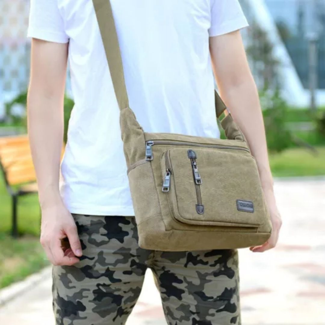 Fitlybuy TravelPro olive canvas shoulder bag with multiple zippered pockets, worn outdoors by a person.