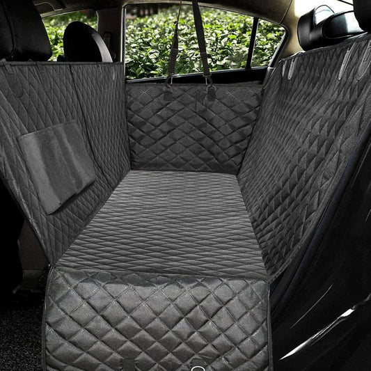 Grey quilted waterproof dog car seat protector installed in a car backseat with storage pocket and side flaps.
