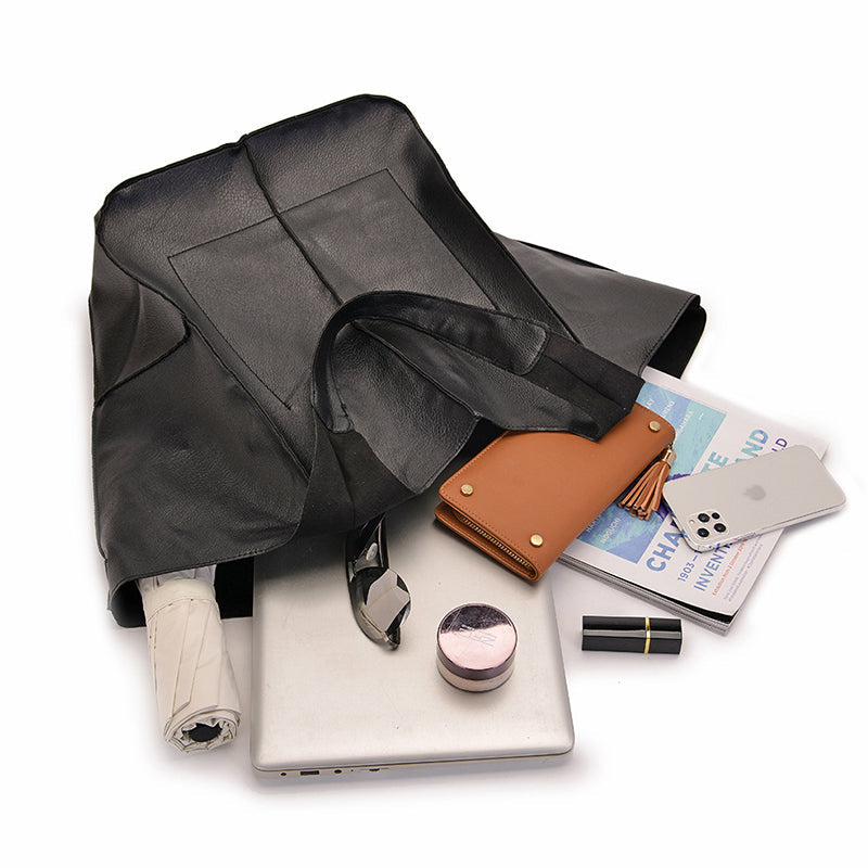 Oversized black leather Fitlybuy weekender bag with a laptop, wallet, phone, and travel essentials spilled out.