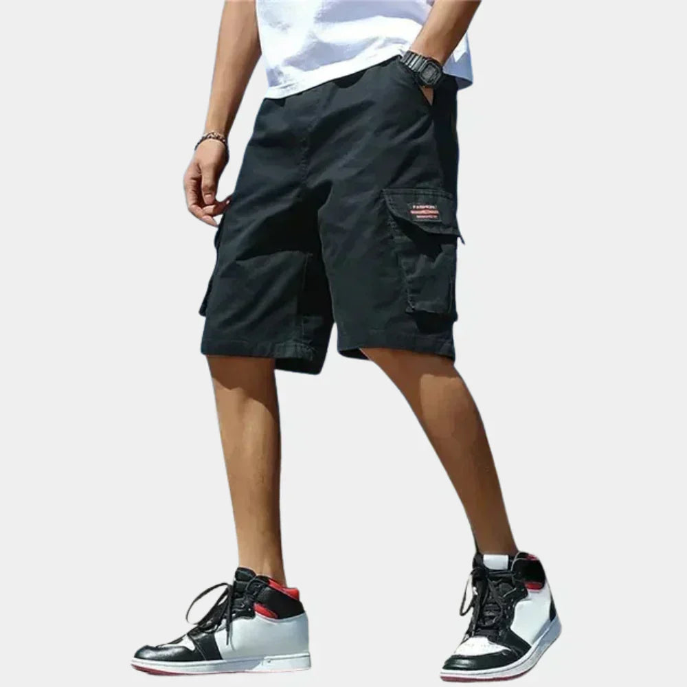 Fitlybuy black loose-fit cotton cargo shorts with side pockets worn by a man in a white tee and high-top sneakers.