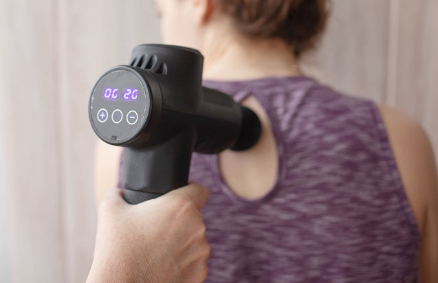 Fitlybuy ProMassage X1 black percussion massage gun with digital display being used on a woman's back.