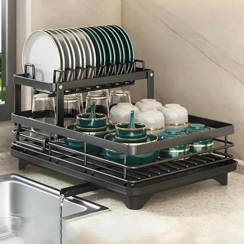 Black 2-tier adjustable dish drying rack with built-in drainboard, holding plates, bowls, and glasses on a kitchen sink.
