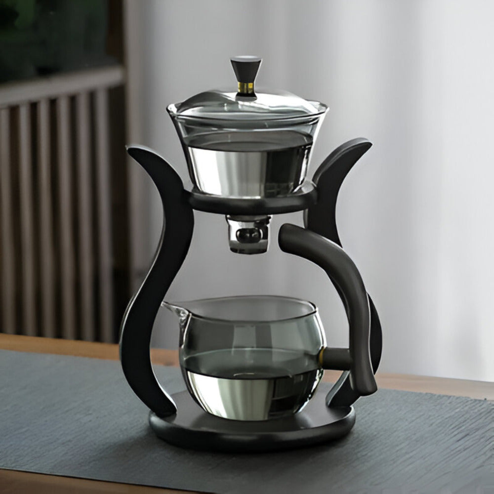 Fitlybuy Artisan magnetic glass teapot with infuser and sleek black stand on a dark mat. Elegant, drip-free design.