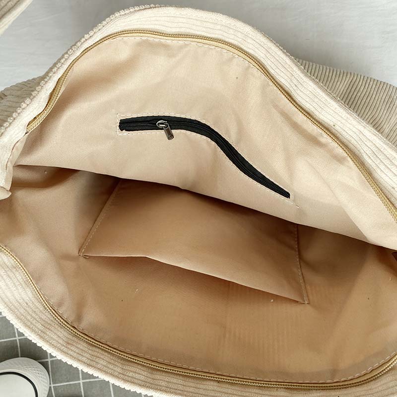 Interior view of a beige Fitlybuy corduroy crossbody bag showing a lined main compartment with a zippered pocket.