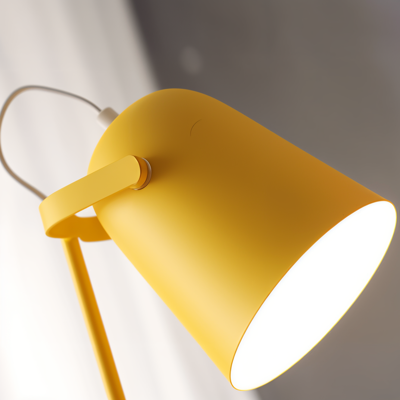 Fitlybuy Nordic yellow Macaron desk lamp with an adjustable tilted shade, emitting bright light in a modern interior.