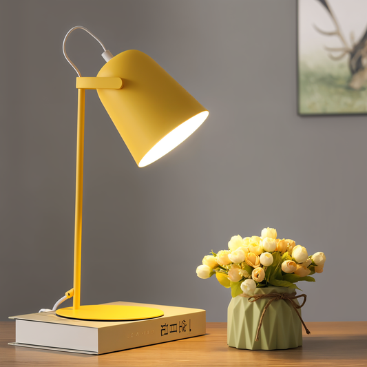 Fitlybuy Nordic yellow adjustable desk lamp on a book next to a small flower pot on a wooden surface.
