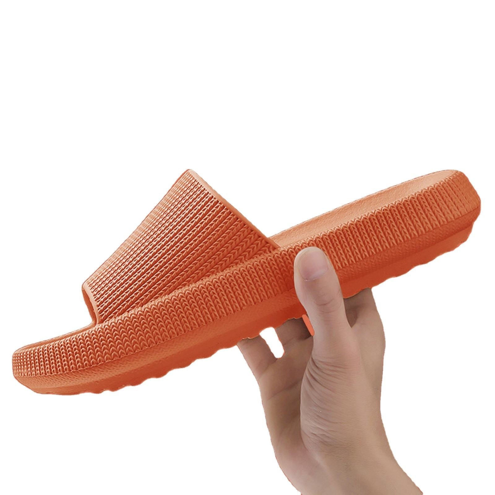 Hand holding an orange Fitlybuy cloud slipper with a textured, thick sole and ultra-soft memory foam design.