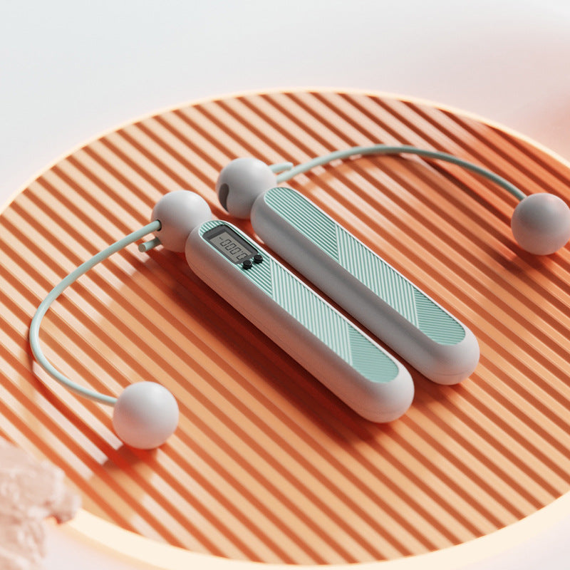 Fitlybuy cordless digital jump rope in mint and white with LCD fitness tracker on an orange ribbed surface.