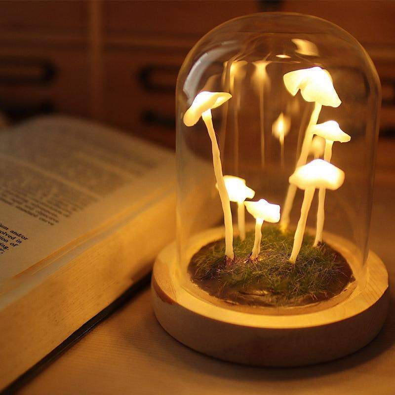 Fitlybuy Enchanted Mushroom DIY glass lamp featuring glowing white mushrooms on a moss base, placed beside an open book.