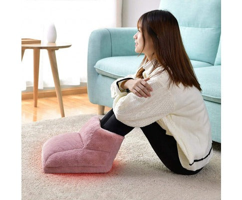 Woman sitting on a rug with feet inside a pink, plush Fitlybuy electric heated warmer in a cozy living room.