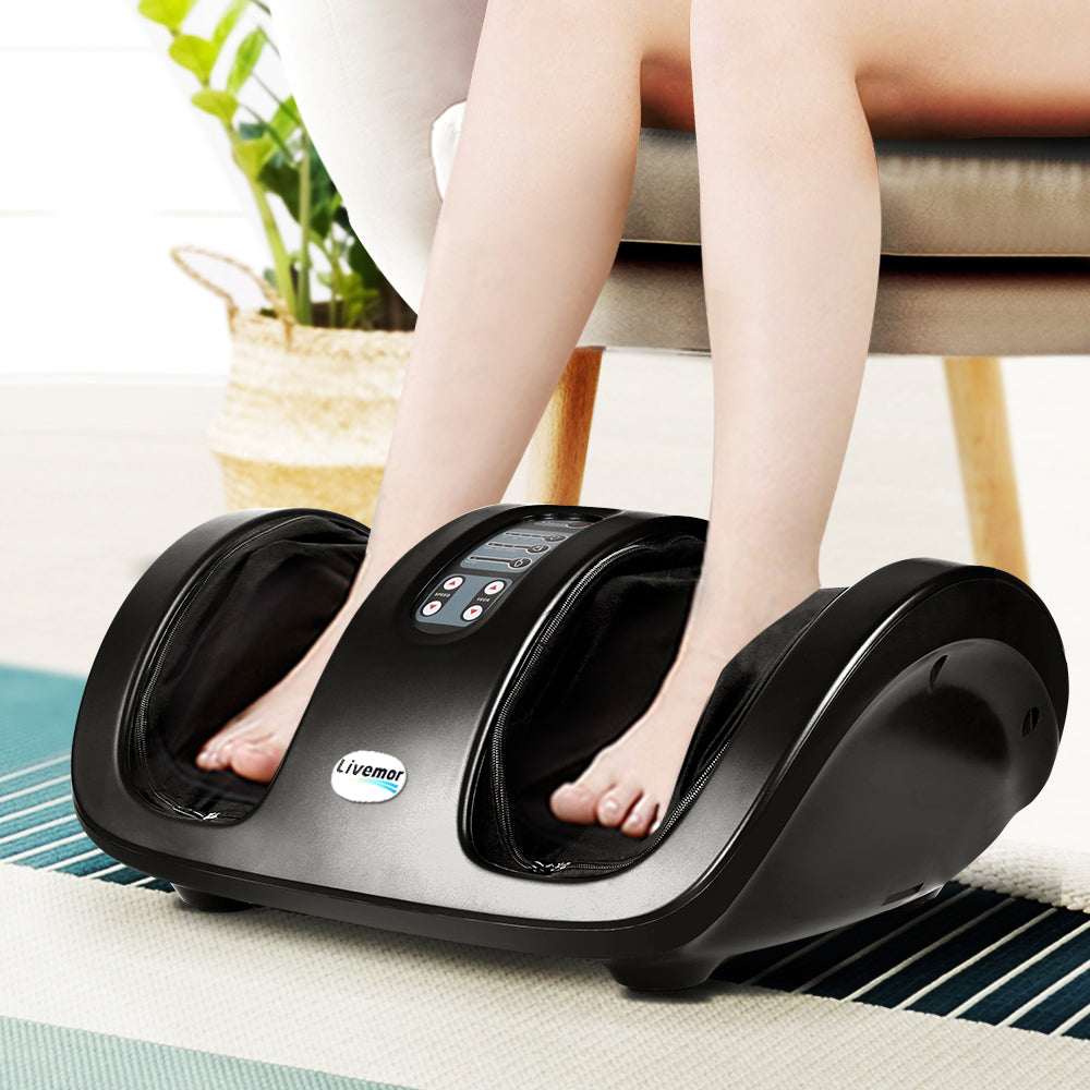 Black Livemor foot massager with deep tissue relief control panel, shown in use on a rug with feet inserted.