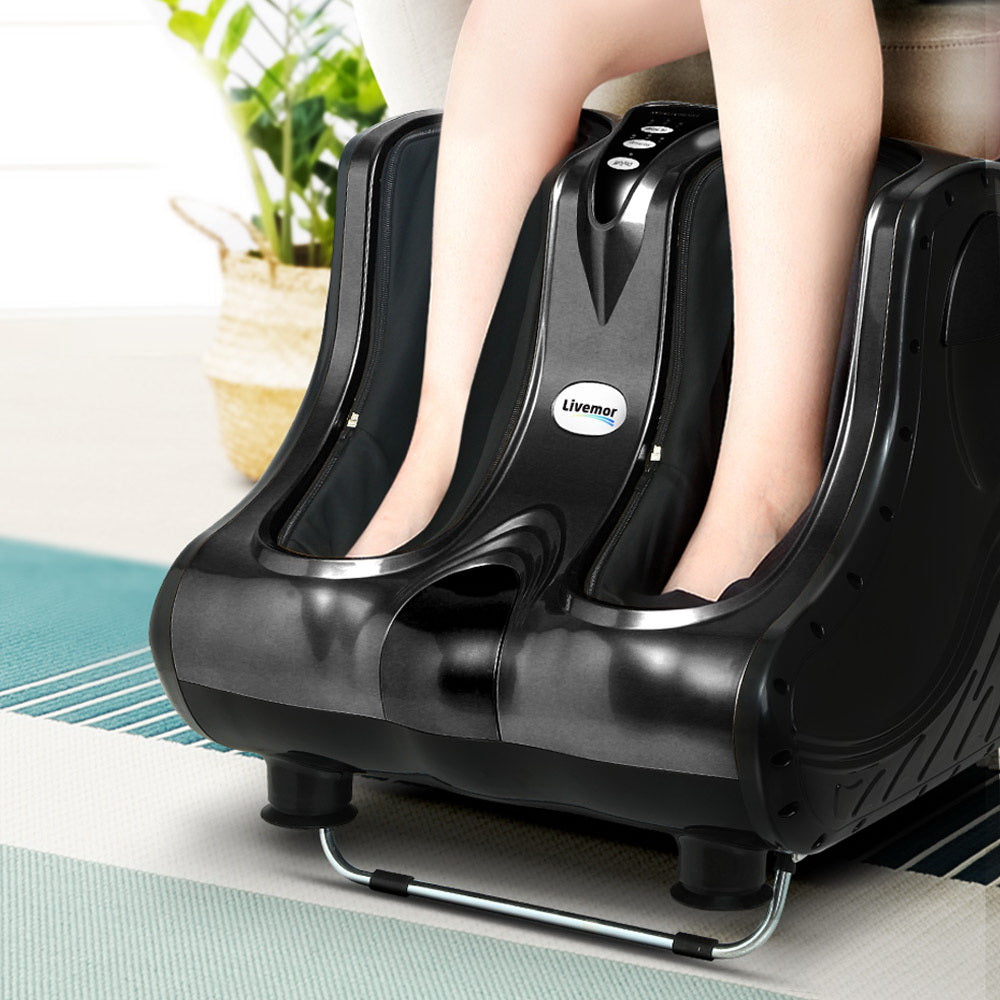 Black Livemor foot and leg massager with control buttons, shown in use on a rug in a bright room.