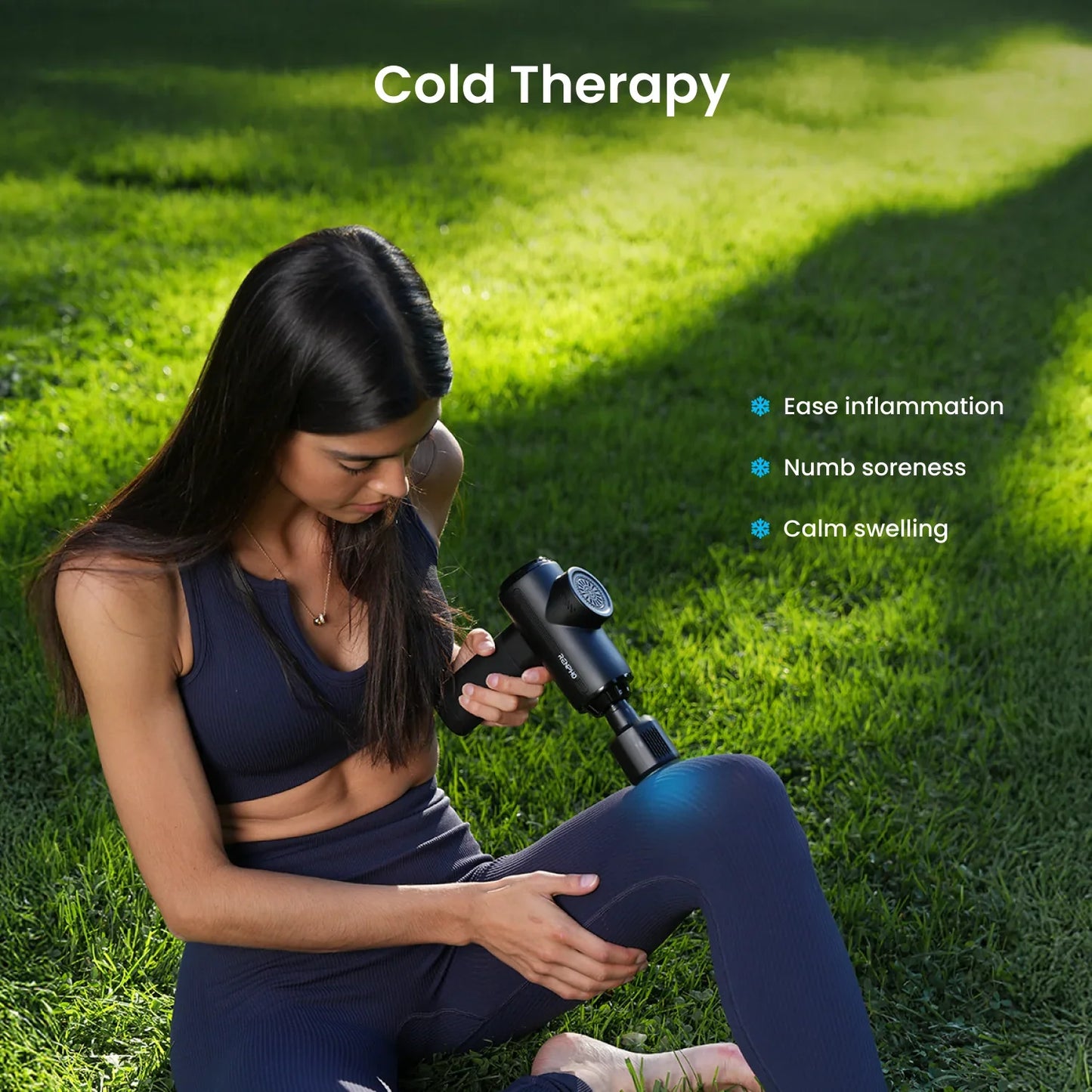 Woman in a park uses a black Fitlybuy Thermacool massage gun on her knee for cold therapy to reduce inflammation.