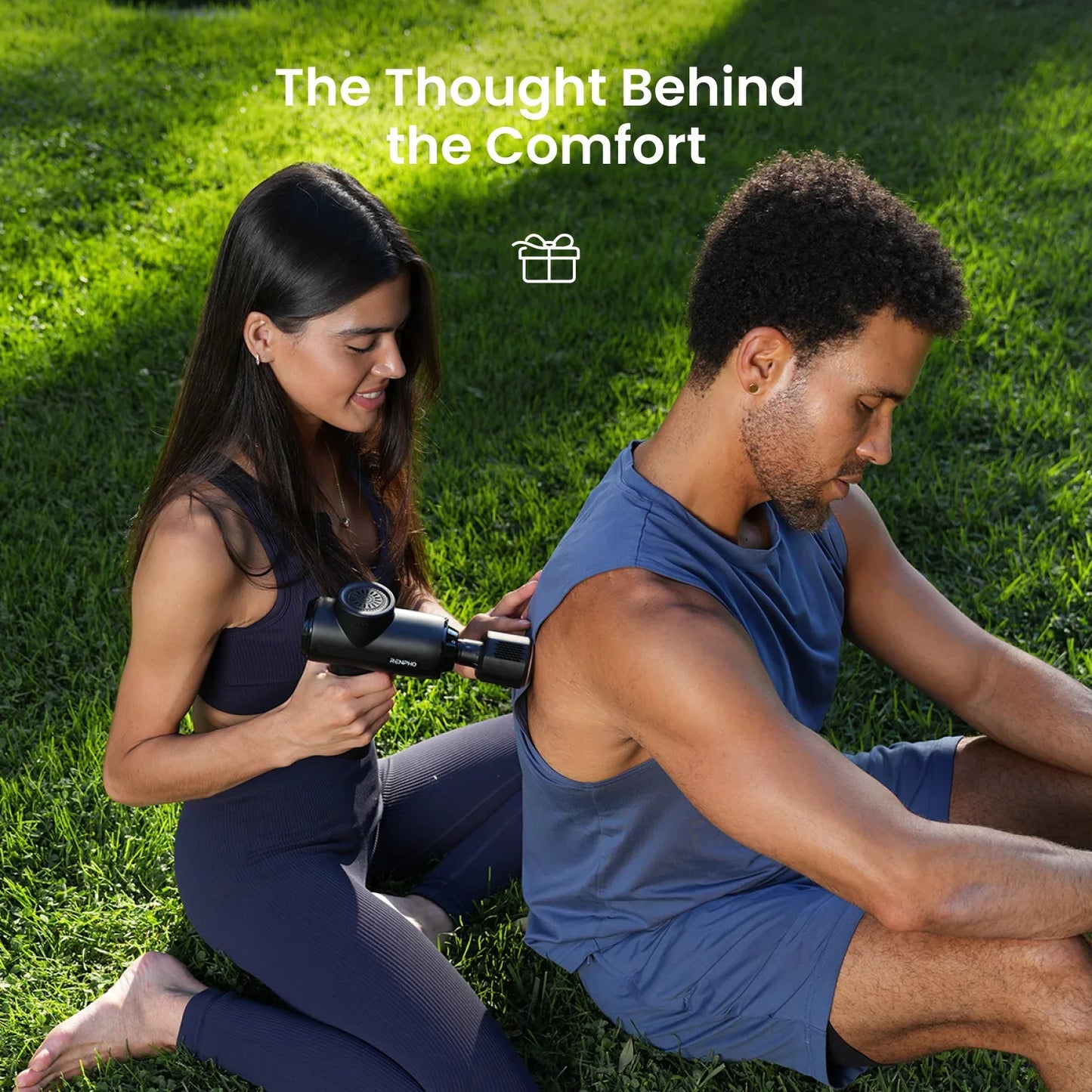 Woman using a black Fitlybuy Thermacool massage gun on a man’s back while sitting on green grass.