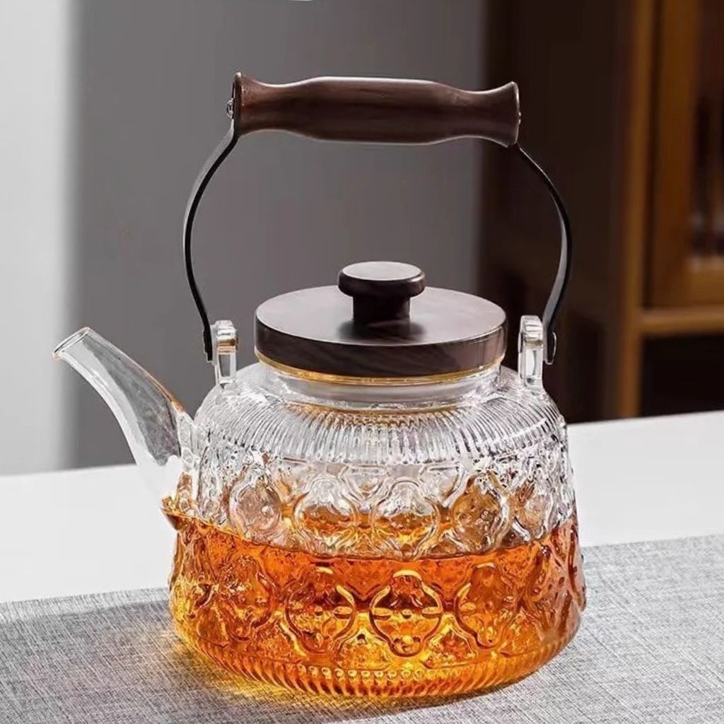 Fitlybuy Zoie glass teapot with textured body, tea infuser, and wooden handle and lid, sitting on a grey table.
