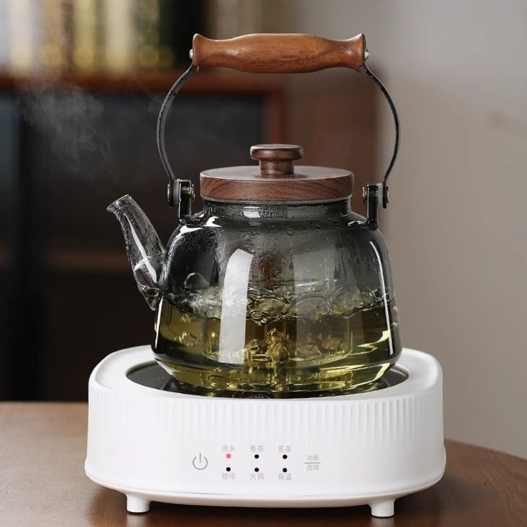 1000ml borosilicate glass teapot with wooden handle and lid, steaming on a white electric stove.