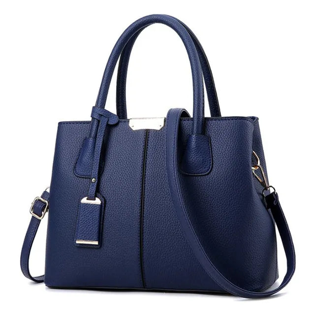 Navy blue, textured PU leather designer-style handbag with top handles, a removable crossbody strap, and gold hardware.