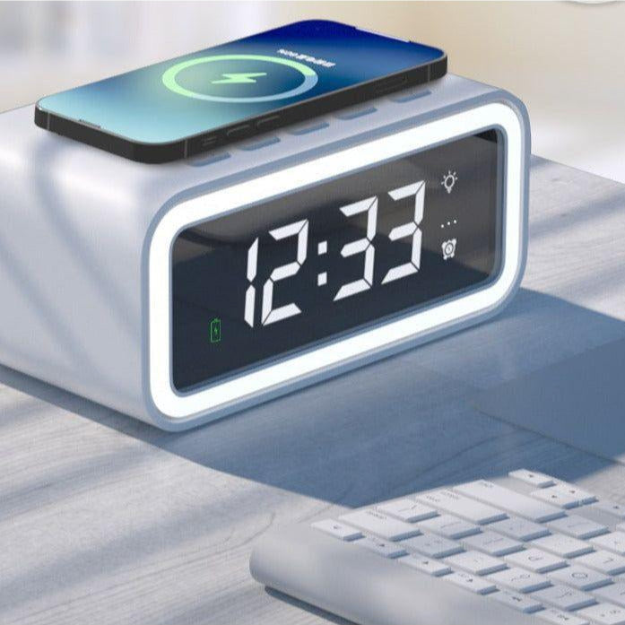 White Fitlybuy 2-in-1 LED alarm clock with Qi wireless charging pad, displaying 12:33 on a desk near a keyboard.