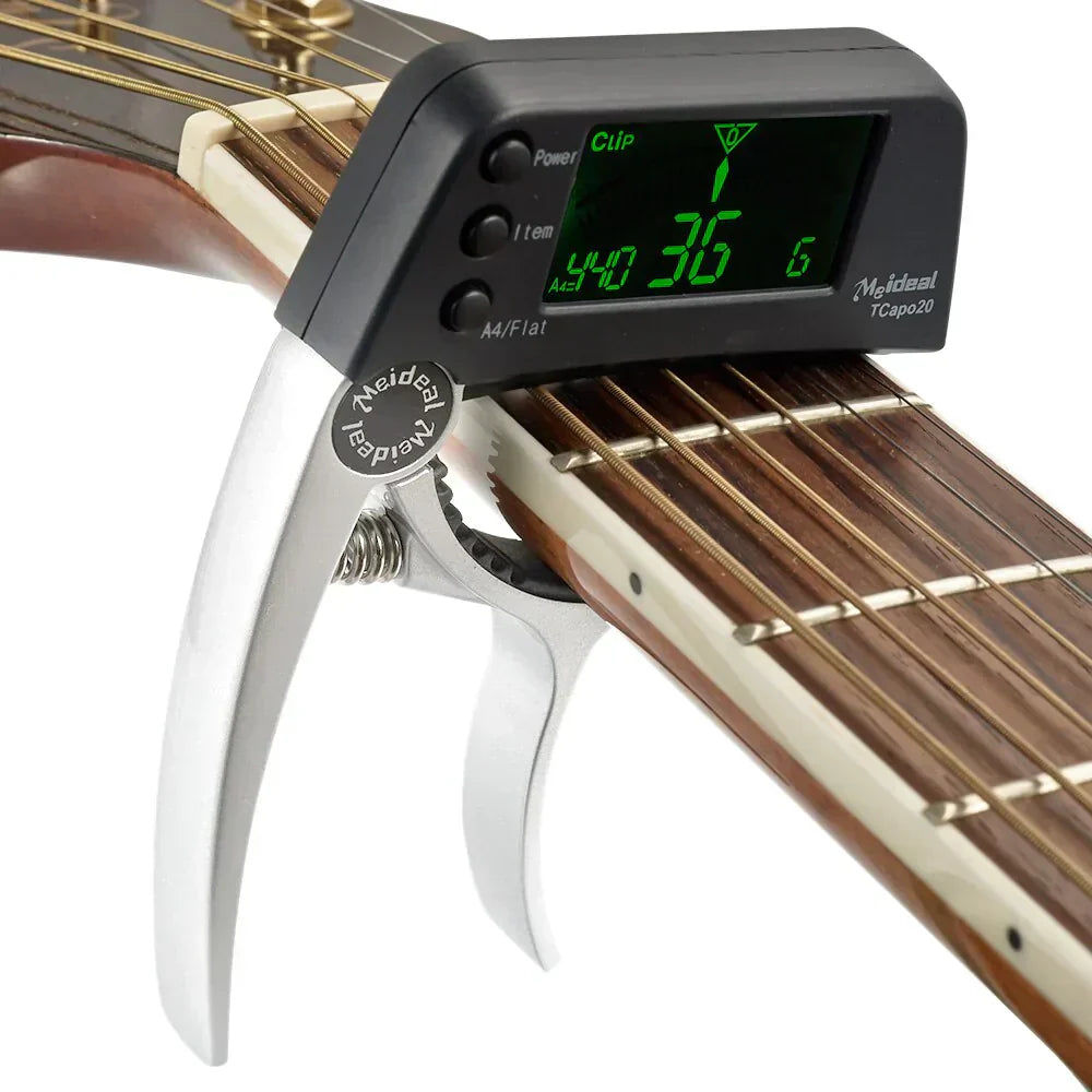 Fitlybuy 2-in-1 silver guitar capo with a black digital tuner screen clamped onto an acoustic guitar neck.