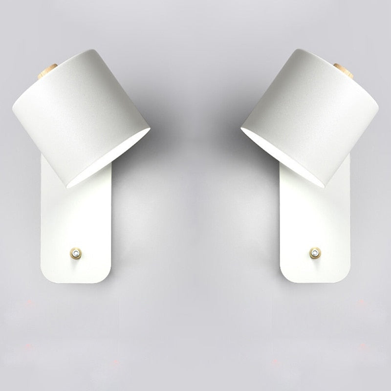 Two modern white LED wall lamps with adjustable cylindrical heads, wood accents, and integrated switches on wall mount.