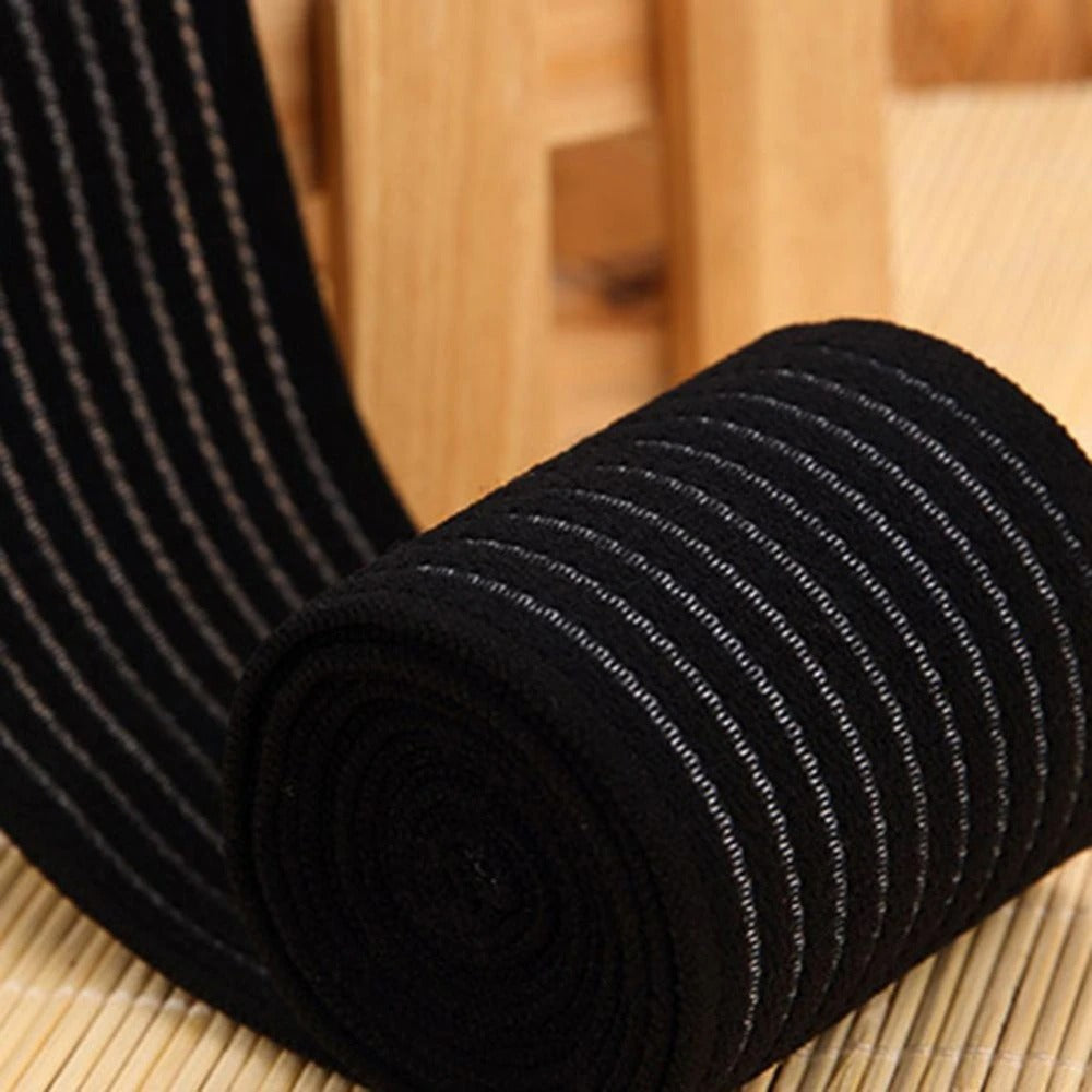 Fitlybuy black high-elasticity compression bandage roll with grey stripes on a light wooden background.