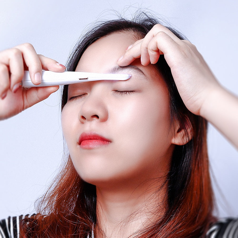 Woman using a white Fitlybuy SoftSkin painless facial hair remover on her eyebrow against a white background.