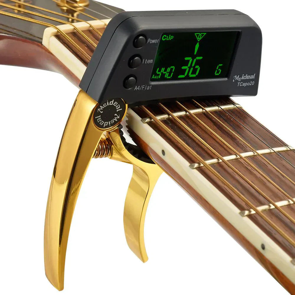 Gold 2-in-1 guitar capo with digital tuner attached to a guitar neck, showing a green illuminated LCD display.