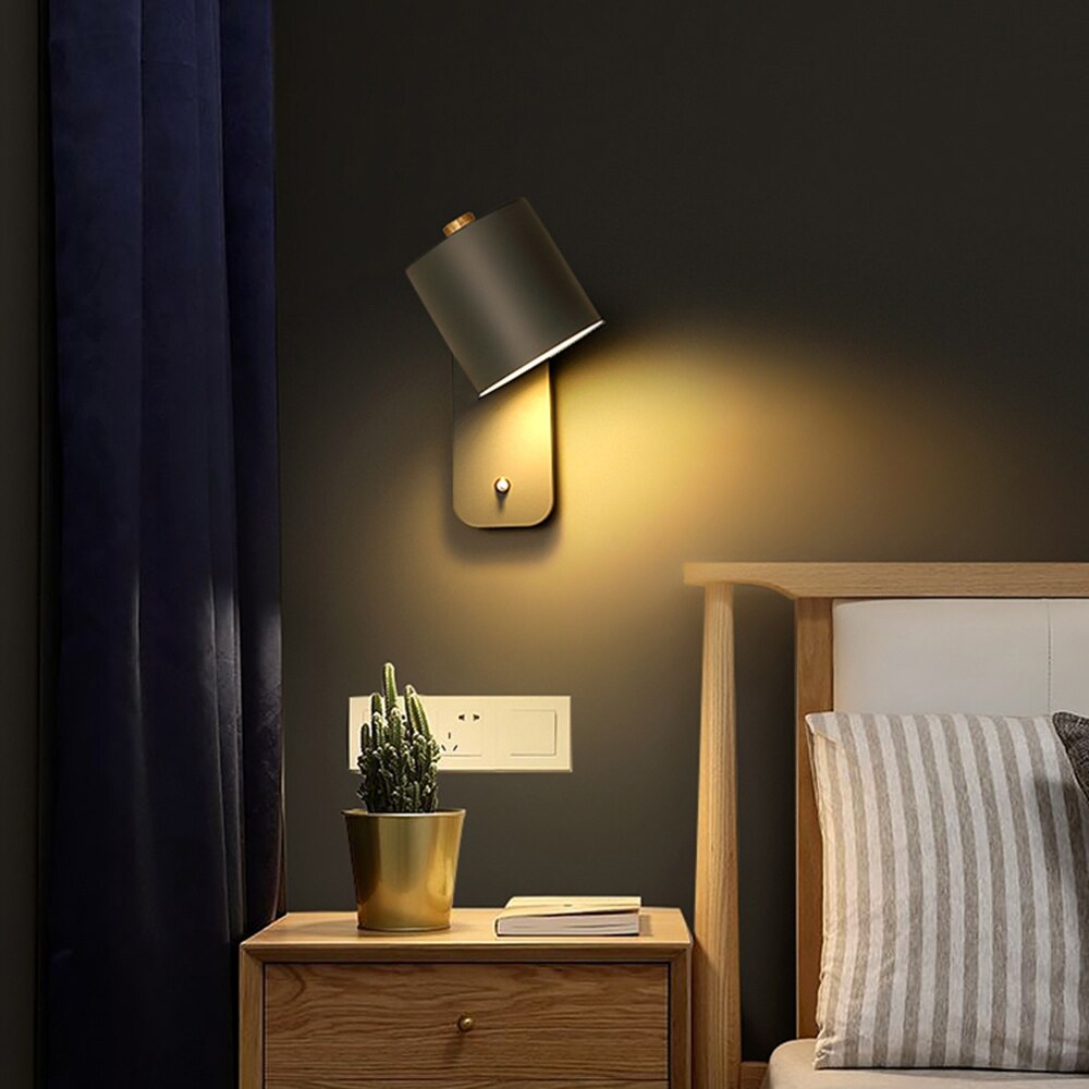 Fitlybuy modern charcoal grey LED wall light with warm light mounted above a wooden nightstand in a bedroom.
