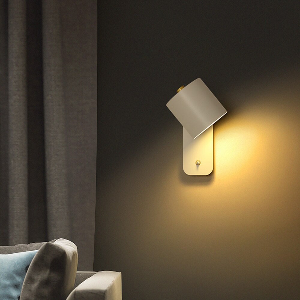 Modern matte white LED wall light with gold switch accent, mounted on a dark wall next to curtains and a sofa.