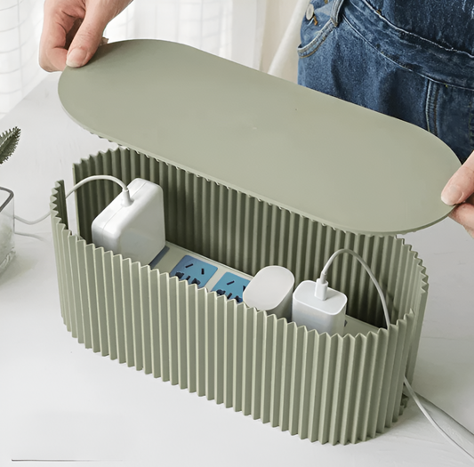 Fitlybuy soft green, oval-ribbed cable organizer box holding a power strip with white chargers on a white table.