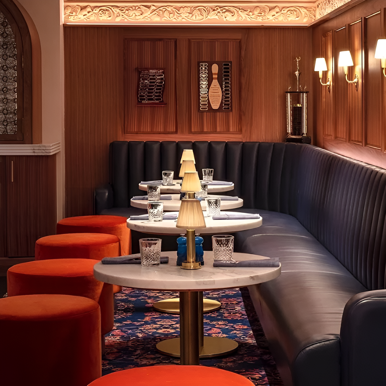 Vintage gold LED table lamp with flared fabric shade on round marble cafe tables in a dimly lit restaurant lounge.