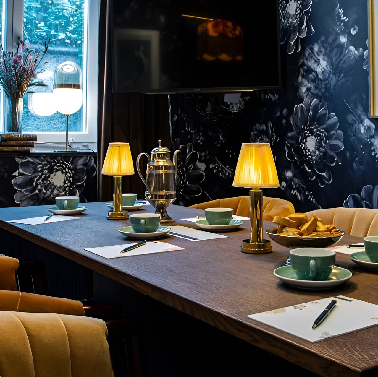 Two gold dimmable Fitlybuy table lamps with pleated fabric shades on a conference table with tea and note pads.
