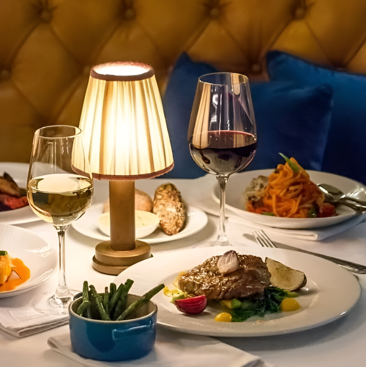 Fitlybuy vintage dimmable aluminium table lamp with fabric shade, glowing on a dinner table with wine and food.