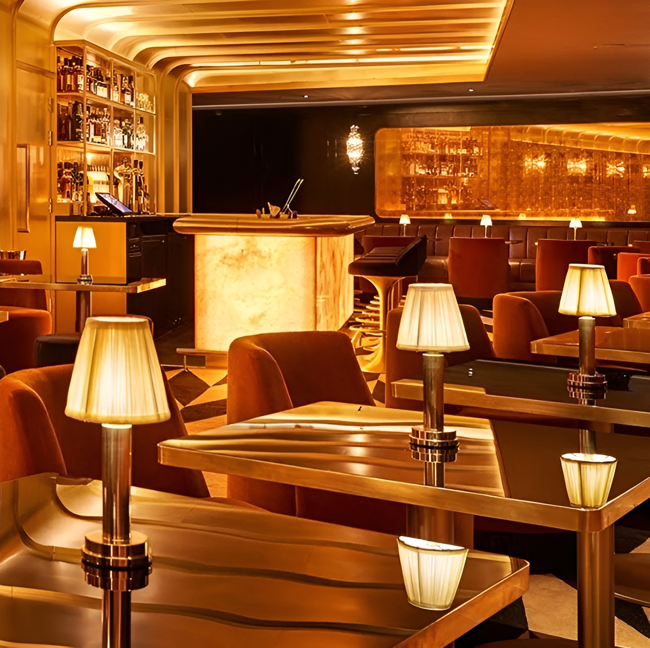 Vintage flare table lamps with fabric shades and gold aluminum bases, glowing on restaurant tables in a luxe bar setting.