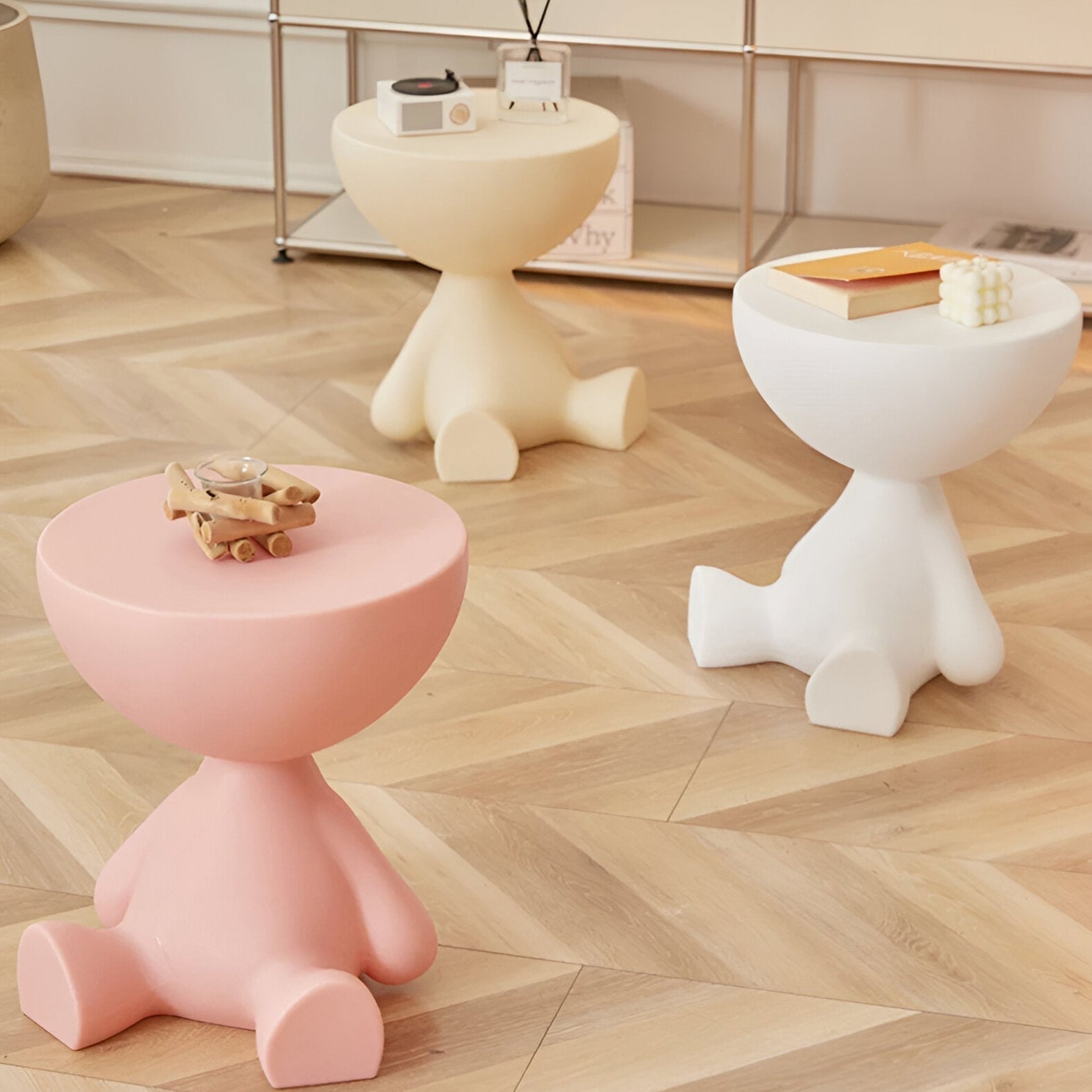 Fitlybuy Ylix round coffee tables with artisan bear-shaped bases in pastel pink, cream, and white on a wood floor.