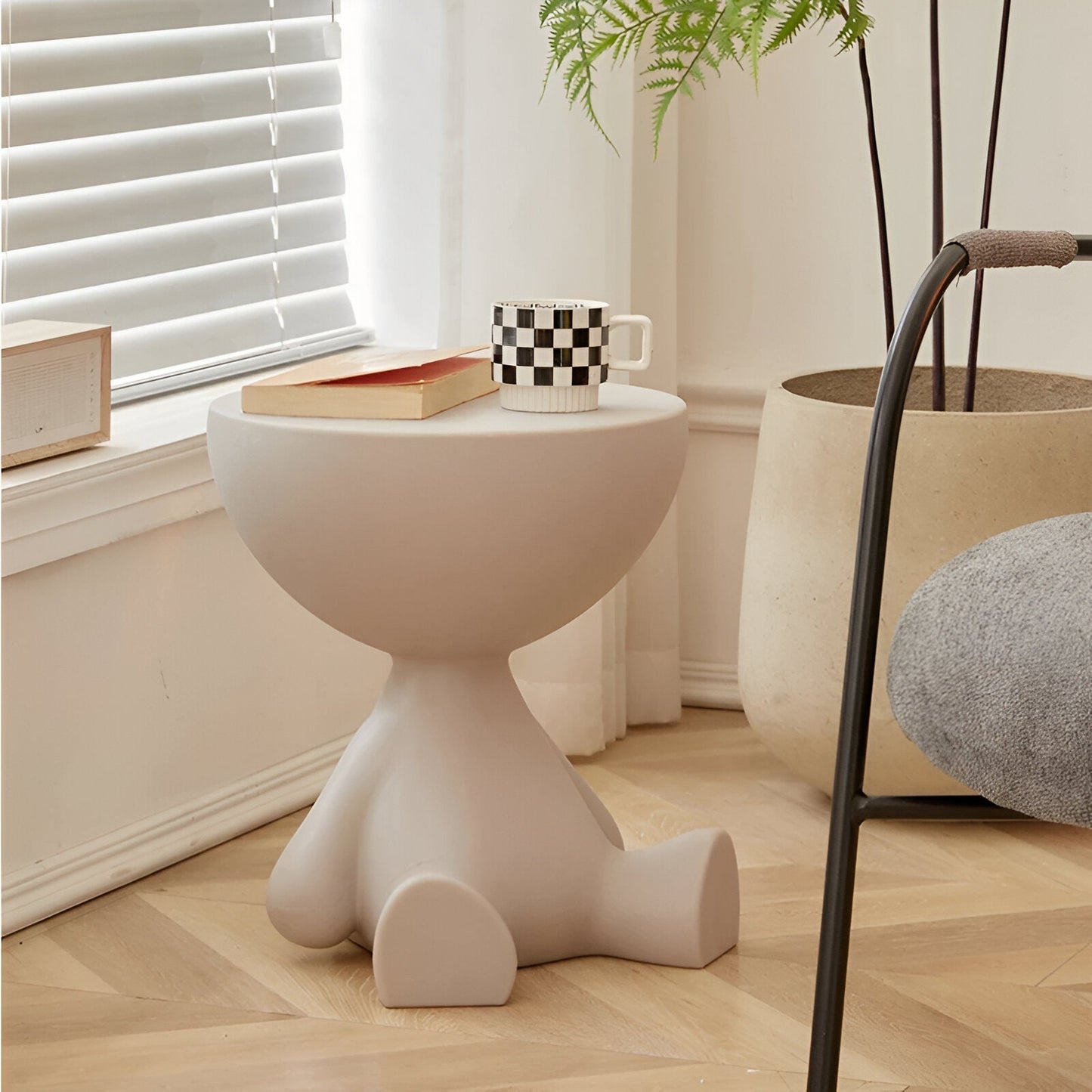 Beige round Fitlybuy Ylix coffee table shaped like a seated figure, styled in a minimalist living room with a mug.