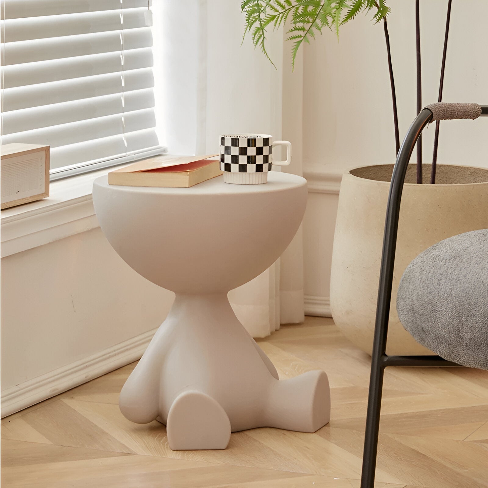 Beige round Fitlybuy Ylix coffee table shaped like a seated figure, styled in a minimalist living room with a mug.