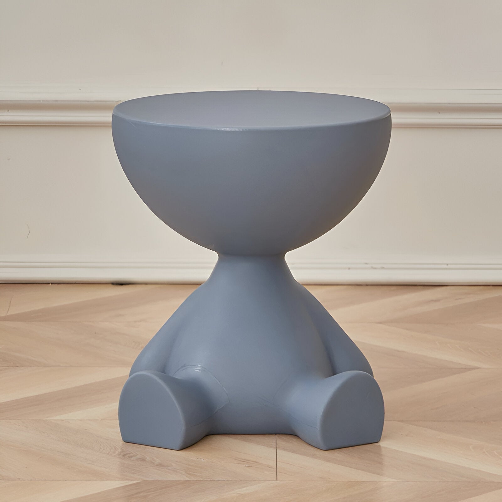 Fitlybuy Ylix round coffee table in matte gray, designed as a playful, sitting figure on a wooden herringbone floor.