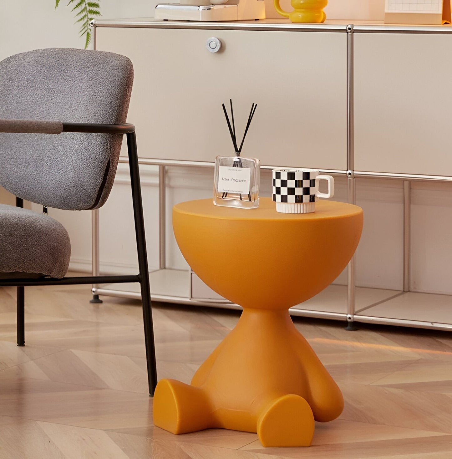Fitlybuy Ylix round mustard yellow table with a unique figure-shaped base, styled next to a chair and cabinet.