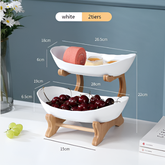 White two-tier serving bowl with wooden stand, displaying snacks and cherries, with dimensions labeled on blue background.