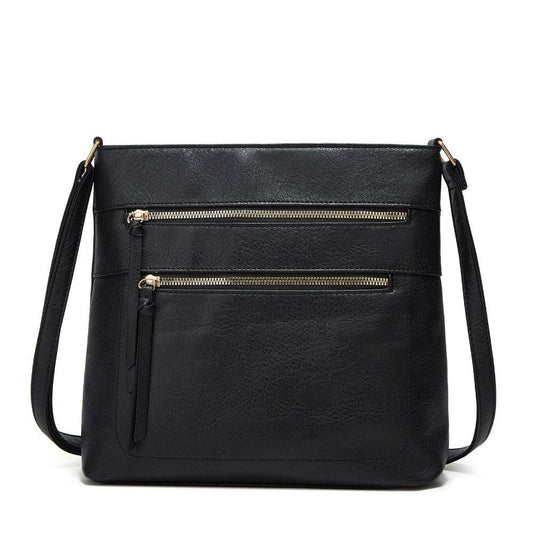 Fitlybuy Nina black genuine leather crossbody bag with two front gold-zippered pockets and an adjustable strap.