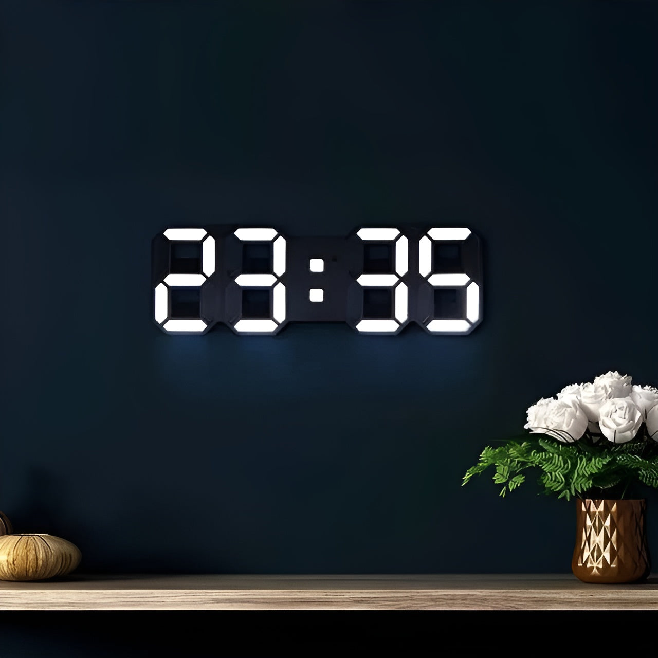 Fitlybuy PixelTime 3D LED digital wall clock showing white time digits on a dark blue wall above a wooden shelf.