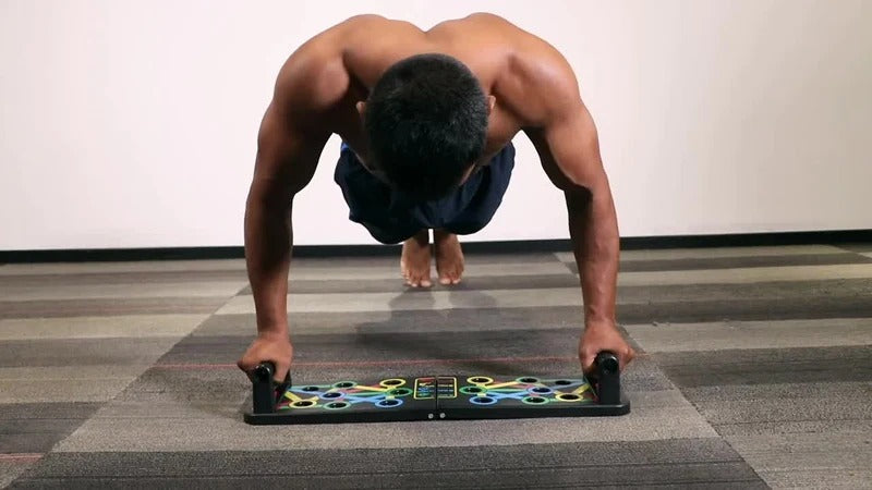 Fitlybuy folding push-up board with color-coded ergonomic grips being used by a shirtless man on a gym mat.