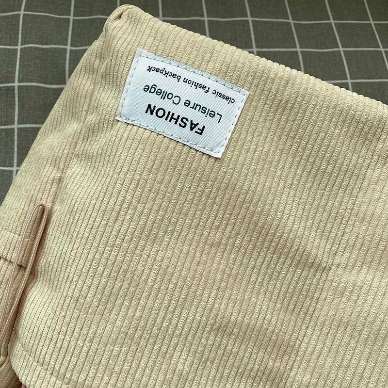 Beige corduroy Fitlybuy crossbody bag with a "Fashion Leisure College" rectangular patch against a grid background.