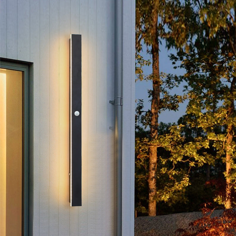 Fitlybuy minimalist black vertical LED wall light with motion sensor installed on a white outdoor house wall.