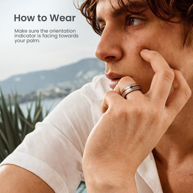 A silver Fitlybuy LYNX smart ring worn on a man’s finger, showing the orientation indicator for proper placement.
